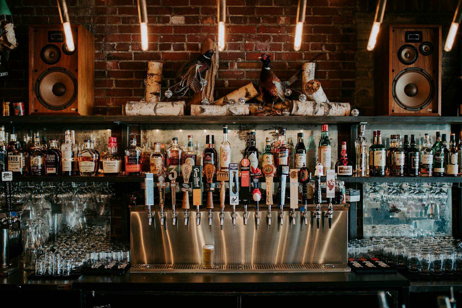 Barra de un bar con botellas y vasos, lista para el servicio